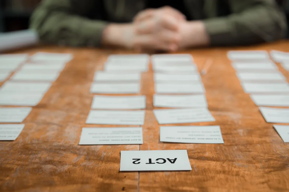 Tarjetas de guion ordenadas en filas sobre una mesa de madera durante la planificación de una película
